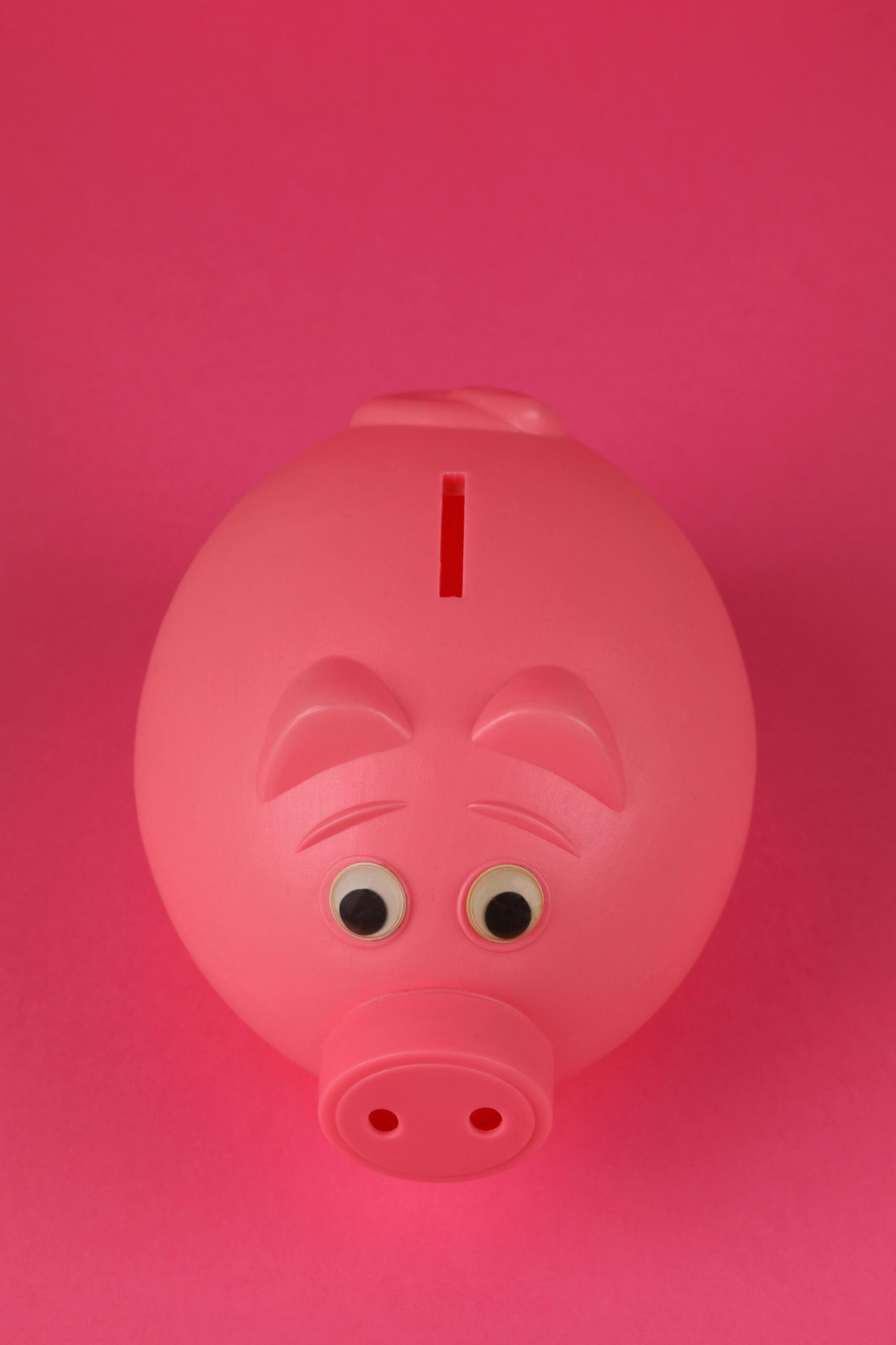 Close-up photo of a pink piggy bank on a vibrant pink background, symbolizing savings and finance.