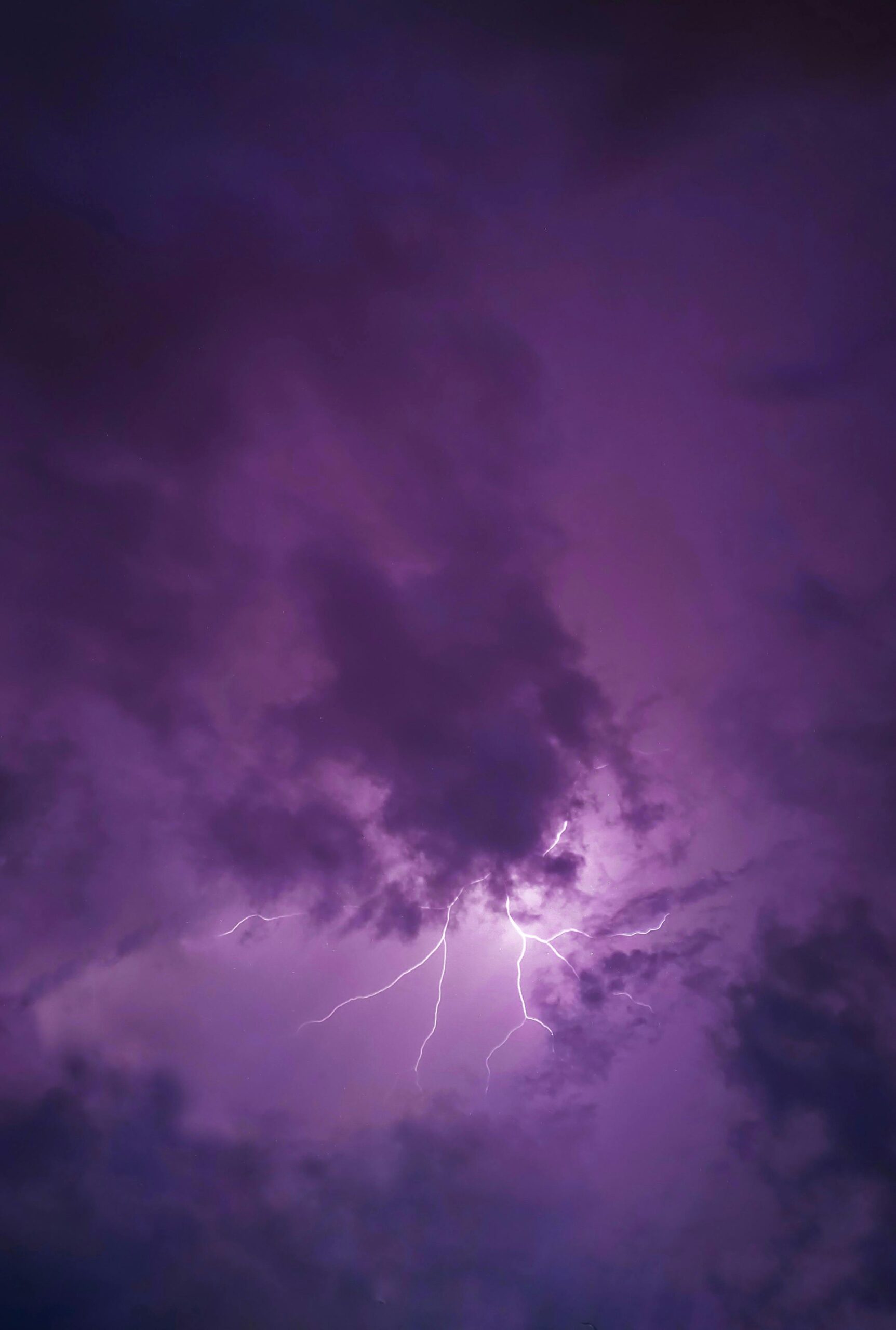 A vivid lightning strike illuminates dark clouds during a dramatic nighttime thunderstorm.