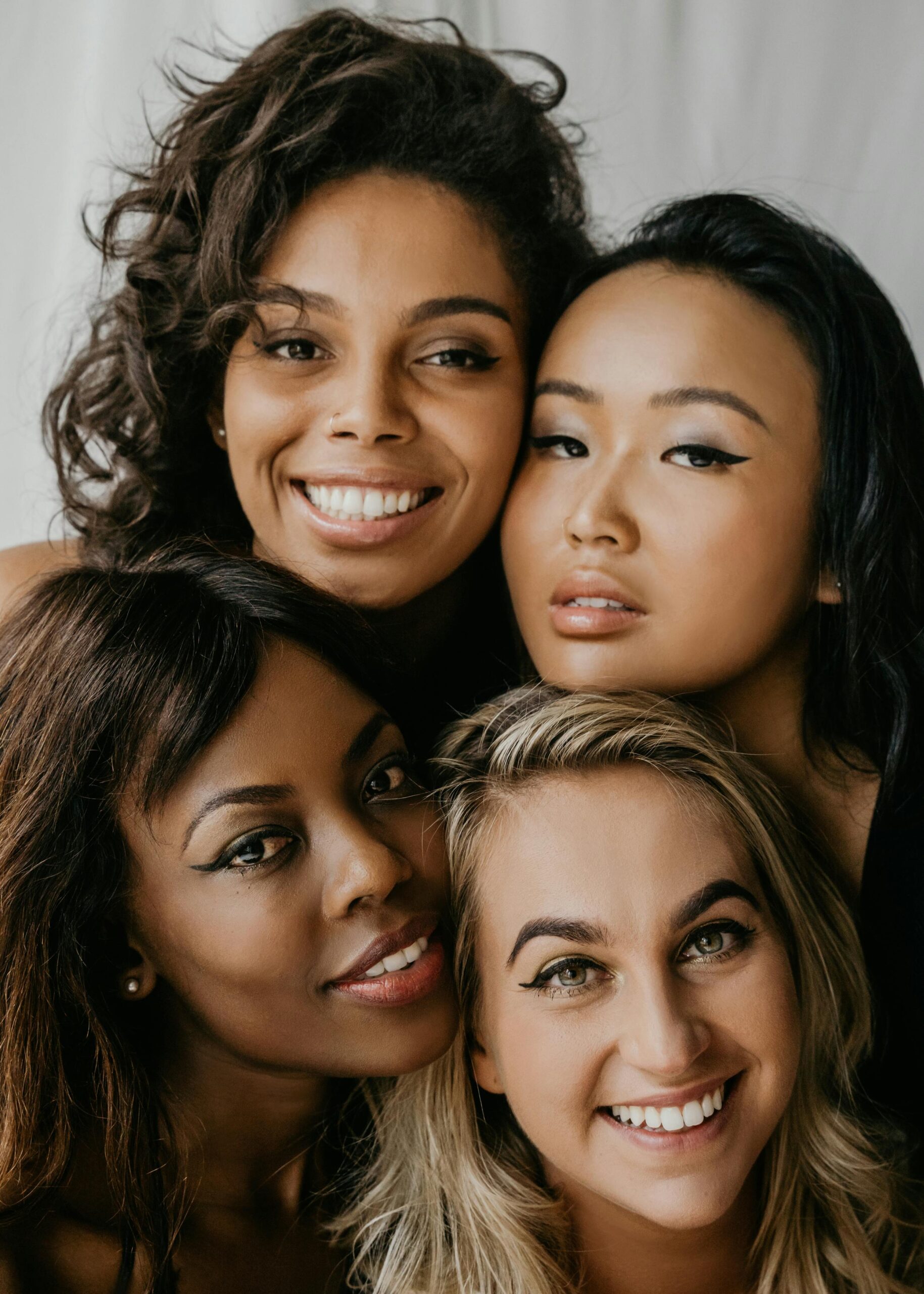 A close-up of four diverse young women smiling and embracing, symbolizing unity and friendship.