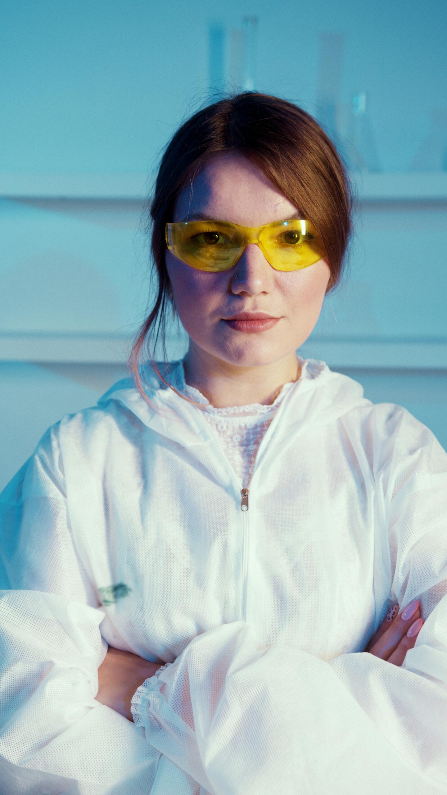 Confident female scientist in PPE with folded arms in a lab.