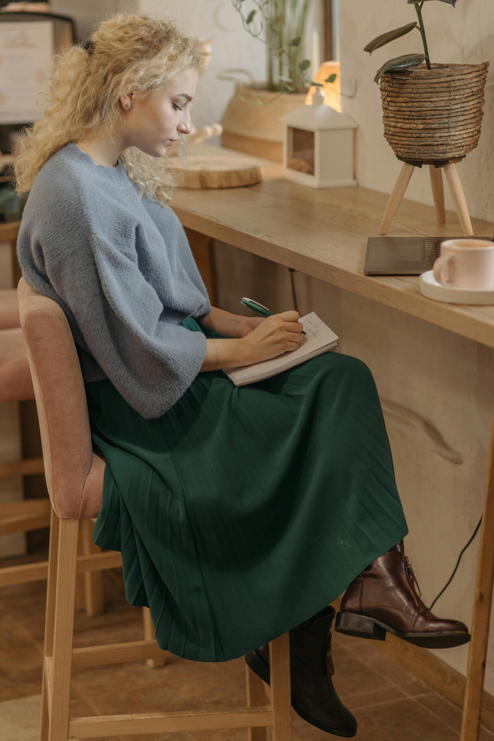 A stylish woman in a cozy café setting writing in a notebook, capturing a moment of introspection.