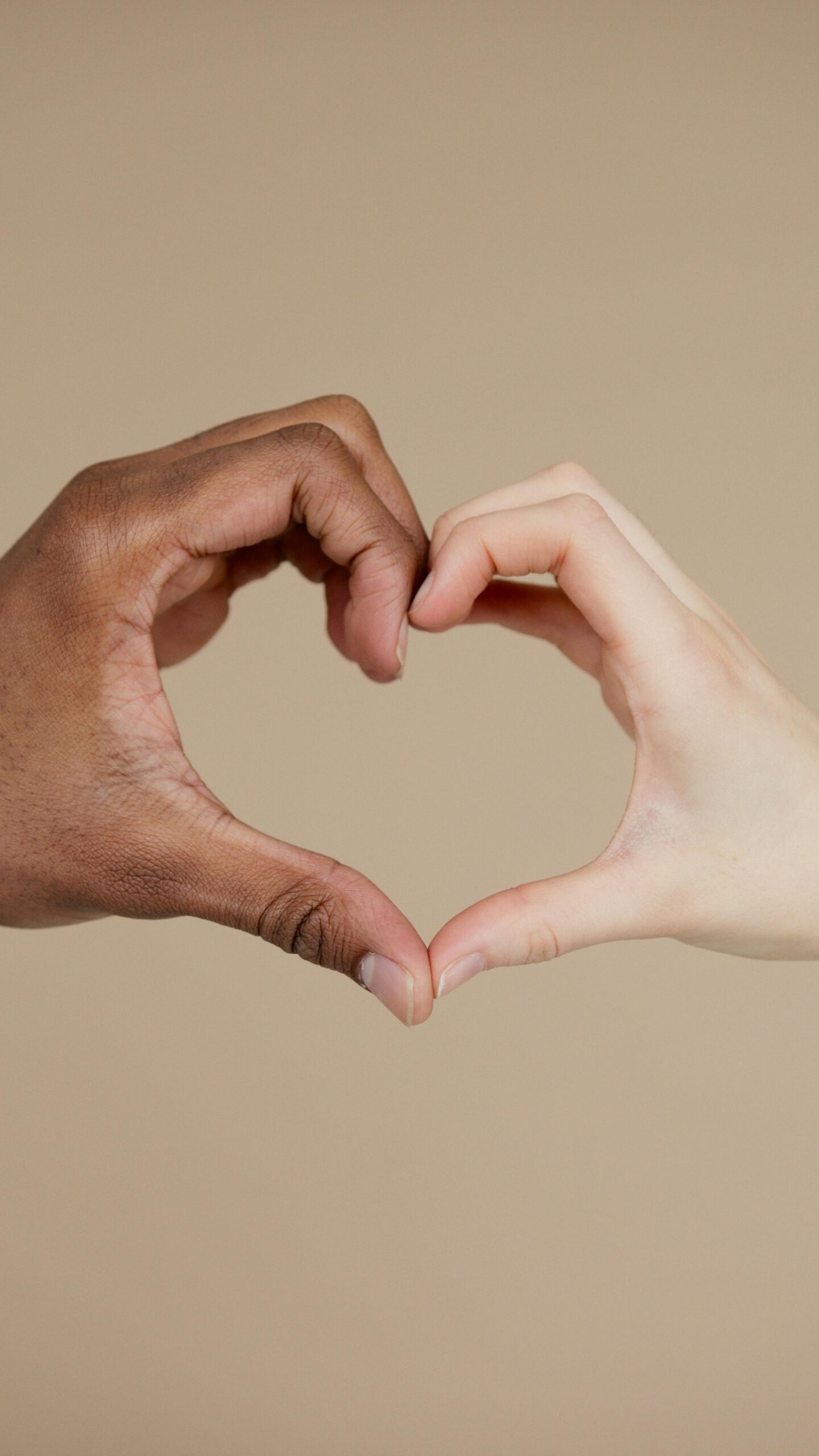 Two hands of different ethnicities form a heart shape, symbolizing unity and diversity.