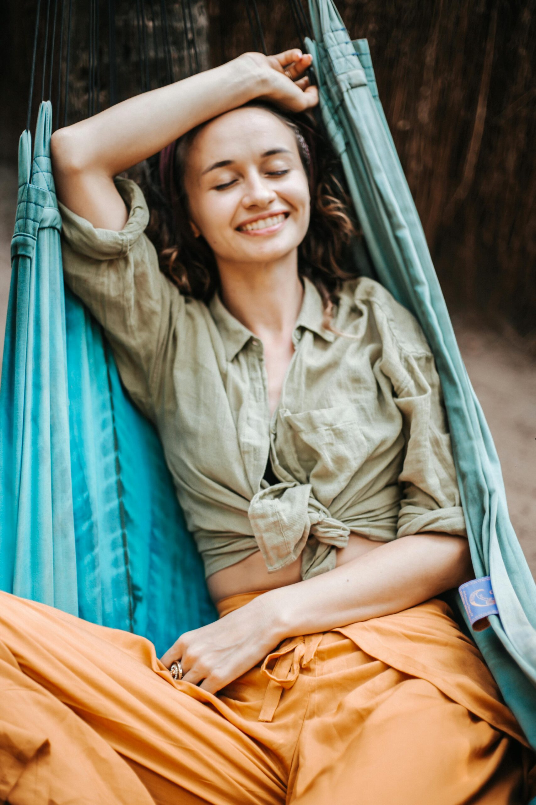 Smiling woman enjoying a calm moment in a hammock, exuding relaxation and leisure.