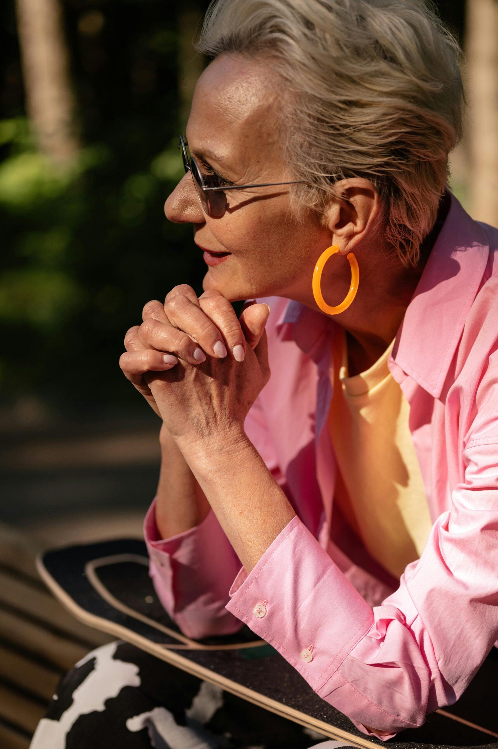 Senior woman in sunglasses and vibrant attire enjoying a relaxed moment outdoors.